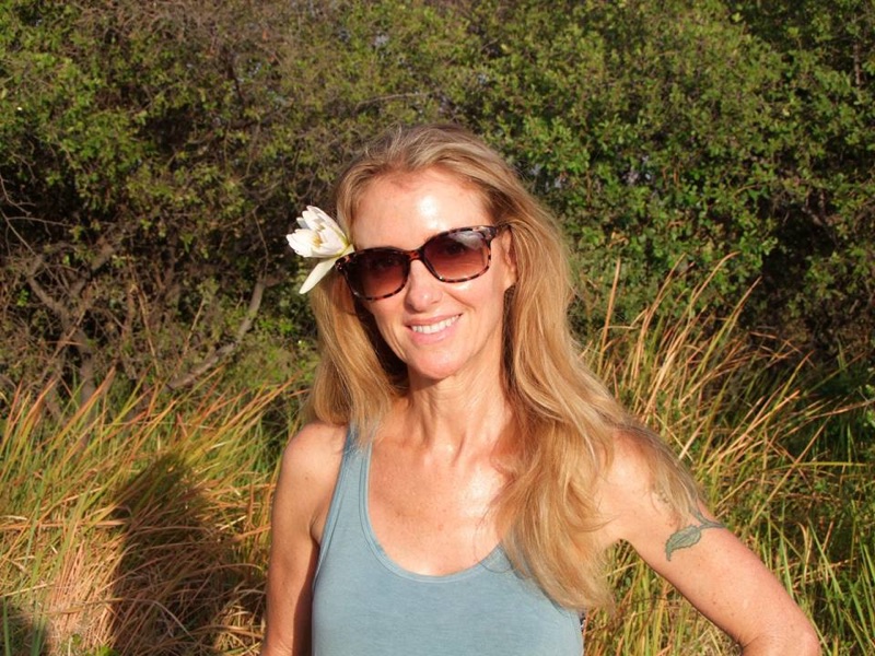Picture of a woman with sunglasses and a flower in her hair. 